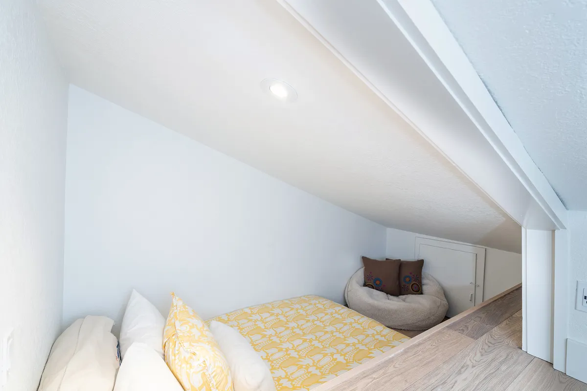 This image shows a cozy nook with a yellow patterned blanket, white pillows, and a bean bag chair, creating an inviting and intimate hideaway perfect for reading, relaxing, or napping.