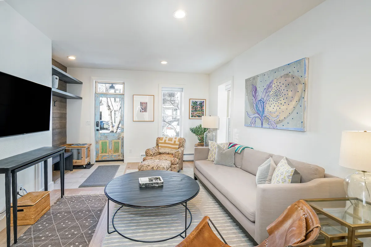 The living room with a cozy sofa, a coffee table, striking artwork on the wall, and a window that offers a captivating view. The inviting atmosphere is ideal for relaxing, socializing, and enjoying the sights outside—as described in the section.